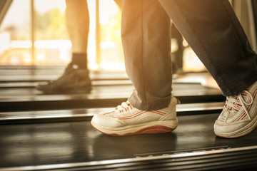 Fototapeta na wymiar Human legs in jogging machine. Senior couple workout in gym.
