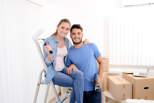 cheerful and happy young couple renovating and painting new home