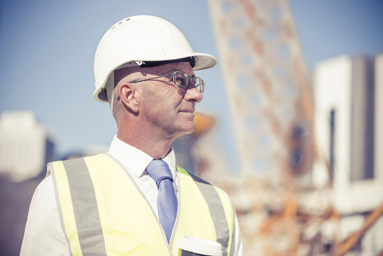 Senior foreman in glasses doing his job at building area on sunn