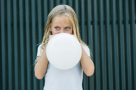 Girl blowing balloon outside