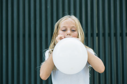 Girl blowing balloon outside