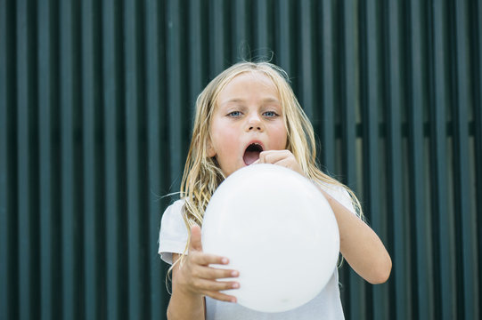 Girl blowing balloon outside
