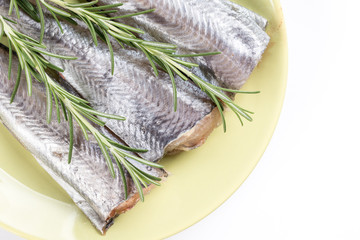 Flat lay above hake fish slices with rosemary branches