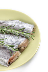 Fresh raw slices of hake fish with rosemary branches on the plate with copy space