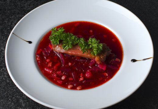 A real Russian borsch on a white plate and black marble with a rib