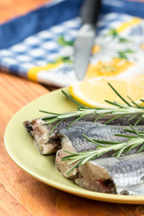 Focus on raw hake fish on the plate with rosemary and lemon