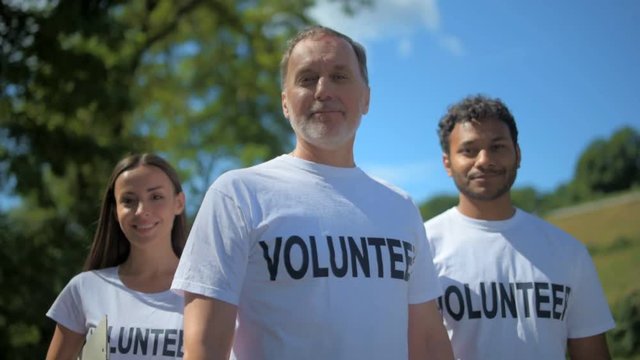 Group of amiling international volunteers tanding in the park