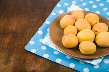 Apricots in a plate on a wooden table