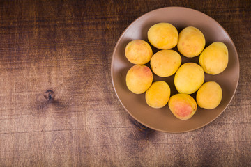 Apricots in a plate on a wooden table