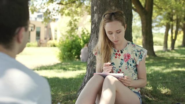 Students sitting in the park and revising for the exam, steadycam sho
