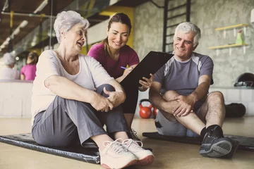 Fotobehang Persoonlijk Senior couple in rehabilitation center. Personal trainer writing records exercises  © liderina