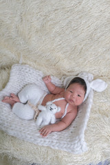 cute asian boy newborn portrait  with white doll one month lie down  on white background fur .