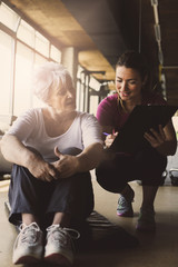 Senior woman workout in rehabilitation center. Personal trainer writing record exercise.