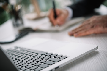 keyboard of laptop with blurred businessman on background