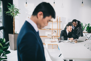 business colleagues in modern office with depressed asian businessman on foreground