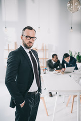 handsome young businessman with blurred colleagues on background