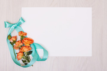 Creative mock up layout made of roses  with copy space on table homemade flat lay. Empty sheet of paper. Mockup with a card and orang rose