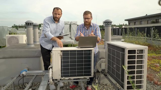 Men standing on the roof and quarrelling about air condition, steadycam shot

