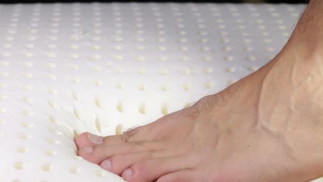 Piede sta premendo su un materasso in memory foam. Schiuma di memoria.