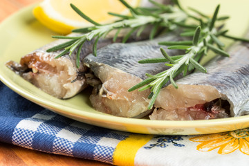 Closeup macro of fresh raw hake fish on the plate with rosemary