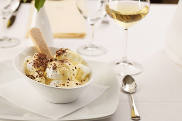 Egg white with vanilla mousse arranged on a plate, Wineglass in background, Traditional dessert in elegant setting, Selective focus with soft light