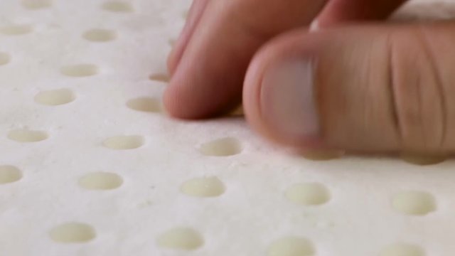 Mani di un uomo che stanno toccando un materasso in memory foam per testare la sua efficacia.