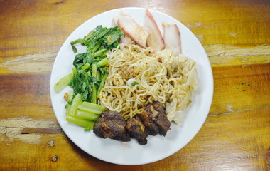 Chinese egg noodles topping slice barbecue pork and stew bone with dumping dressing sweet black sauce on plate