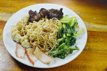 Chinese egg noodles topping slice barbecue pork and braised bone with dumping dressing sweet black sauce on plate