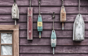 Closeup of colorful floats hanging outside a fisherman's cottage. The image is weathered to add...