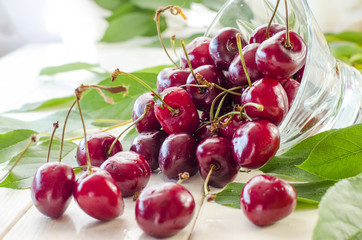 Ripe maroon cherries in a glass vase and a jar