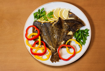Baked flounder with vegetables on wooden background