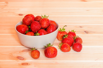 Ripe red strawberries in bowl on  wooden table. Selective focus