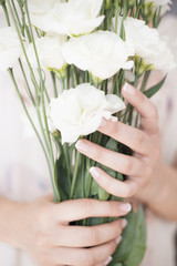 A young girl hand holding a large bouquet of fresh white flowers. Bright feminine lifestyle