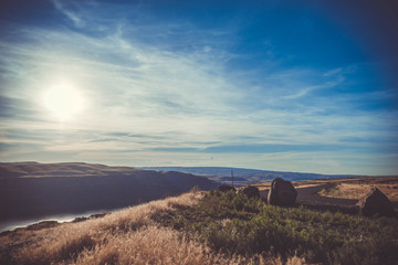 Beautiful sunset or sunrise in mountains taken on a grassy hill with a dramatic sky, clouds, sun and rocks.