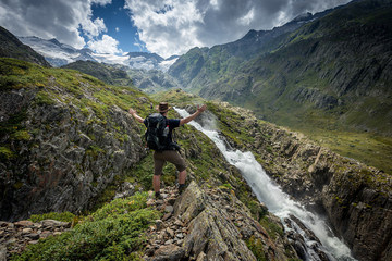 Wanderer geniesst Aussicht auf Wasserfall im Urbachtal, Berner Oberland