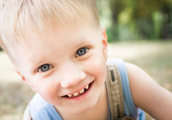 Portrait of a happy little boy in a summer park.