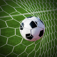 Obraz na płótnie Canvas Soccer football in Goal net with green grass field.