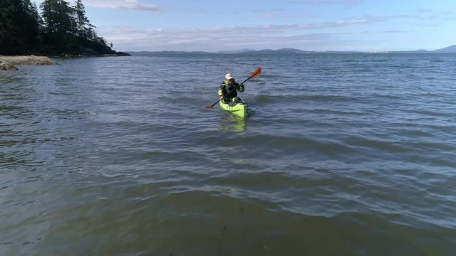 Drone Flying Low By Older Man Kayaking Ocean Coast Slow Motion