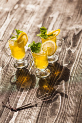 Yellow drinks with mint and lemon on dark rustic wooden background, selective focus