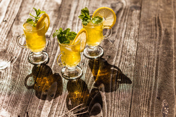 Obraz na płótnie Canvas Yellow drinks with mint and lemon on dark rustic wooden background, selective focus
