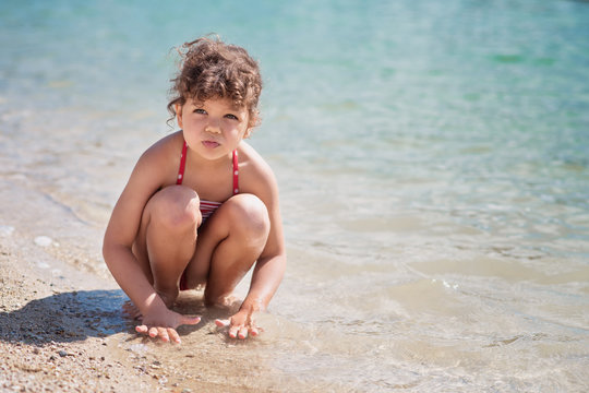 Portrait of little girl playing in shallow water on beach
