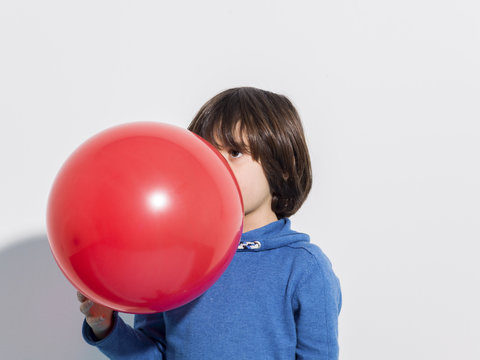 5 year old boy blowing a red balloon