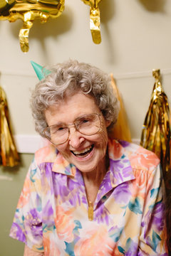 elderly woman smiling wearing birthday hat