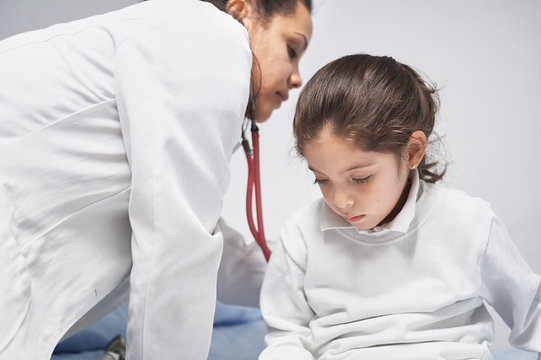 Doctor is doing an exam on a young girl with a stethoscope