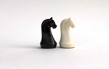 Chess pieces. White and black knight on white background