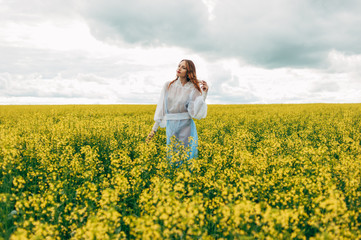Fototapeta premium Beautiful girl in a dress among yellow flowers in a field