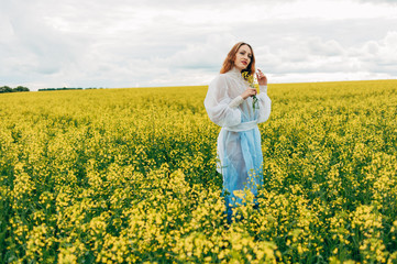 Beautiful girl in a dress among yellow flowers in a field