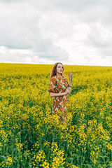 Fototapeta premium Beautiful girl in a dress among yellow flowers in a field