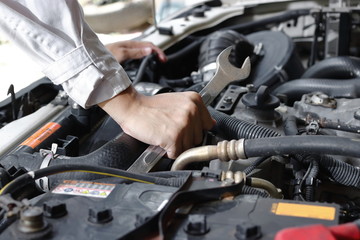 Fototapeta na wymiar Hands of mechanic with wrench repairing engine of motor car under car hood.