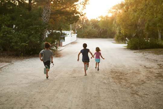 Rear view of children running along the sandy track